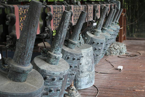 Many ancient Chinese bells, carved with exquisite patterns and engraved on the side of an old wooden building in China's rural areas, stand next to each other like small blacksmiths' hammers