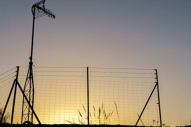 istock Television antenna and wire mesh fence at sunset 2230212042