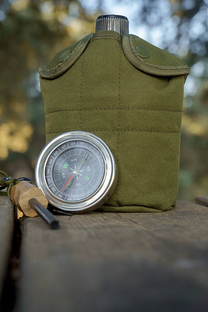 istock Compass, canteen and firesteel resting on wooden surface in nature 2230212070