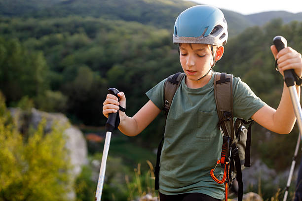 Boy wearing climbing gear while hiking on mountain on sunny autumn day