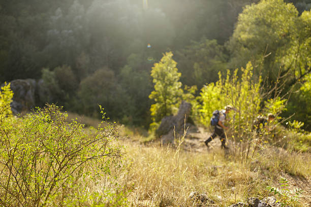 Active mature man hiking with his son in rocky mountains on sunny day
