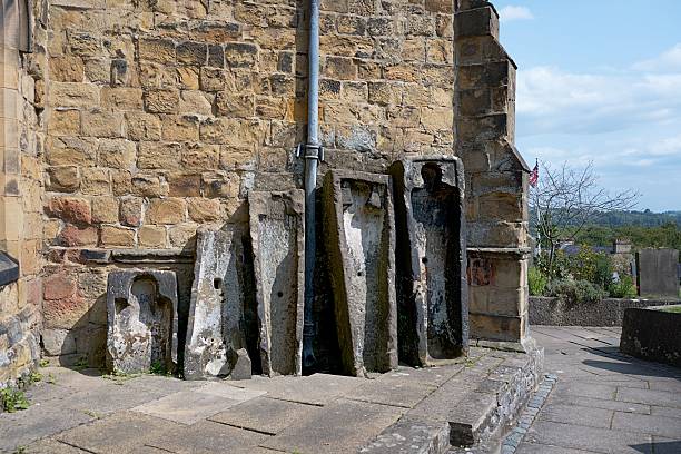 istock Ancient carved stone coffins with weathered textures against a brick wall. 2230219994