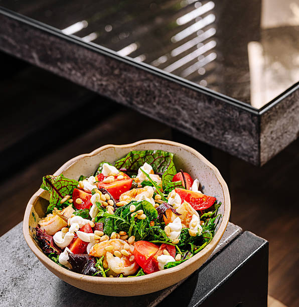 istock Delicious mixed green salad with shrimp and fresh vegetables on a modern table 2230223994