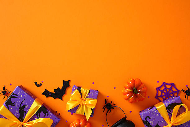 istock Halloween flat lay with gift boxes, pumpkins, spiders, bat, and web on vibrant orange background 2230224584