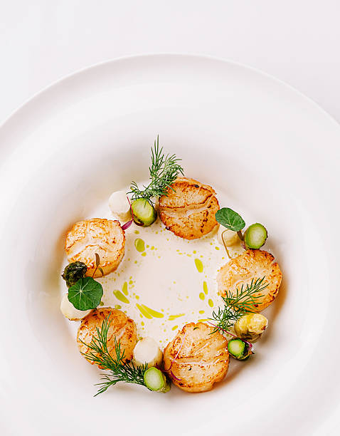 istock Creative culinary presentation with scallops and herbs on a white plate 2230229157