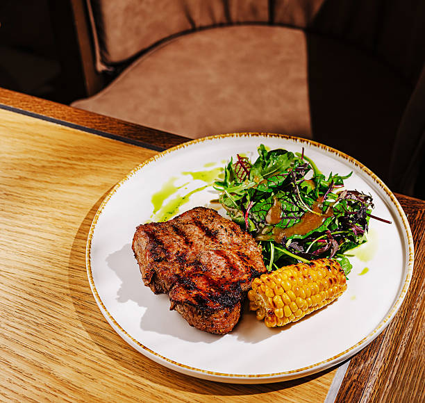 istock Grilled steak served with salad and corn on a wooden table 2230230743