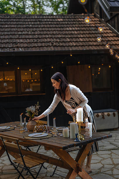 istock Brunette woman adding a vase with flowers to a set table 2230231961
