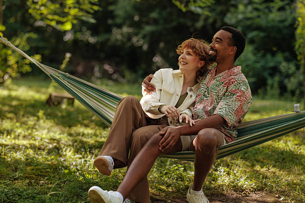 istock Couple sitting in a hammock inside a park 2230237235