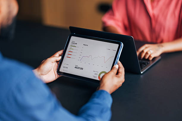 istock Two Professionals Analyzing Financial Data on a Tablet and Laptop in Office 2230239940