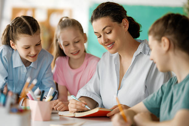 istock Happy kids and teacher at school 2230243565