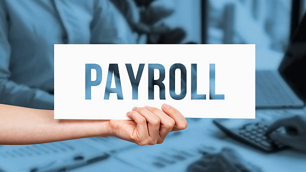 istock Human hand holding a paper on which has been written - Payroll 2230244111