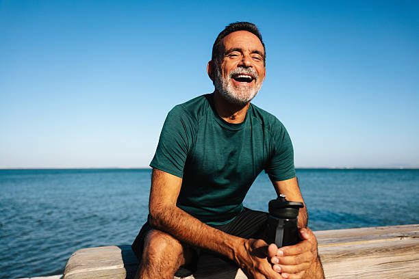 istock Mature man relaxing outdoors smiling by the ocean on a sunny day 2230245367