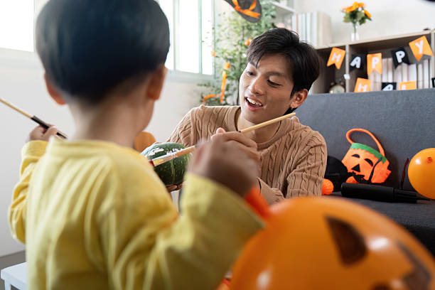 istock Halloween Crafts. Father and son painting pumpkins together. 2230247708