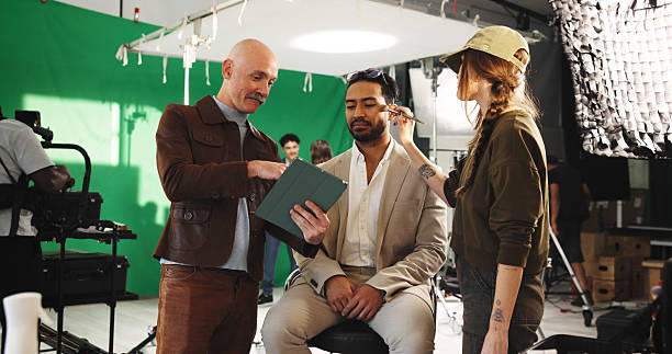 istock People, actor and director with clipboard in studio for scene notes, feedback and filming advice. Team, makeup and preparation with supervisor for movie production, performance guide and script lines 2230248662