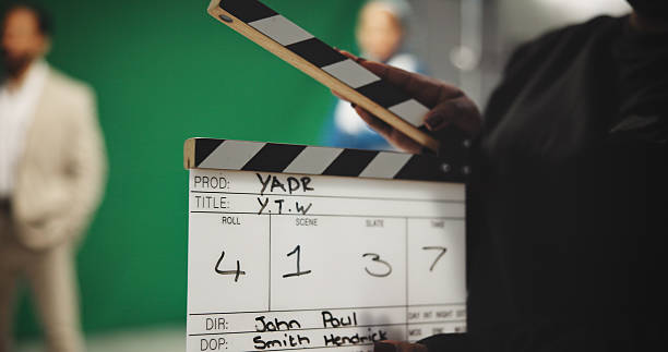 istock Person, hands and production studio with clapperboard for action, take or behind the scenes in set. Closeup, director or producer with movie slate, green screen or reel for film cut, number or roll 2230248687
