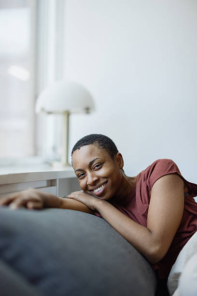 istock Young black woman relaxing on sofa smiling at camera 2230251501