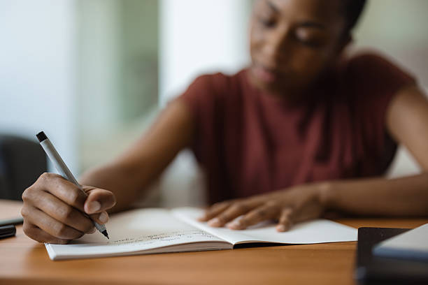 istock Young black woman writing notes in notebook at home 2230251583