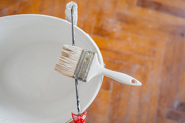 A paint brush on a paint bucket in an empty apartment under renovation.
