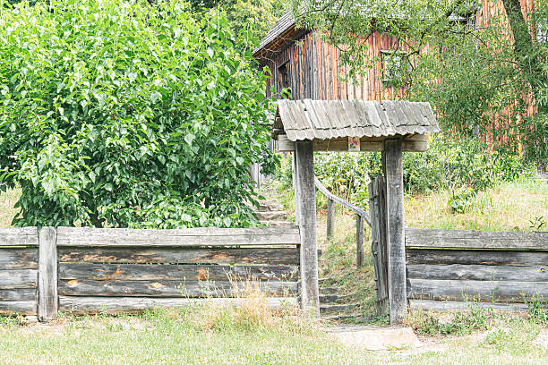 Weathered wooden fence, open-air pavilion, vertical slats, horizontal rails, rustic structure, aged wood, pitched roof, overlapping shinglesplanks, greenery, lush foliage, naturalistic photography,