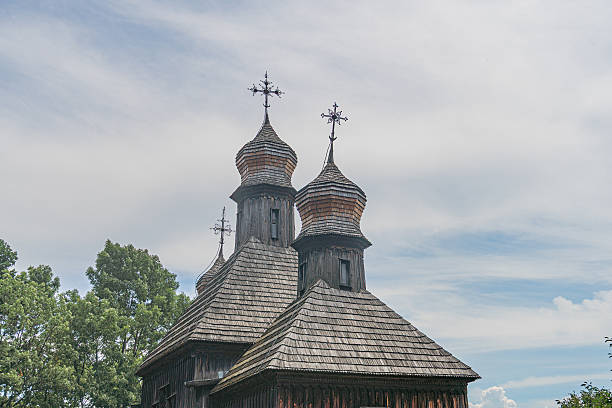 istock Ancient wooden Orthodox church in a rural Central European setting, characterized by multiple domes and a weathered appearance Blue sky with clouds contrasts earthy tones No people present, suggest 2230254943