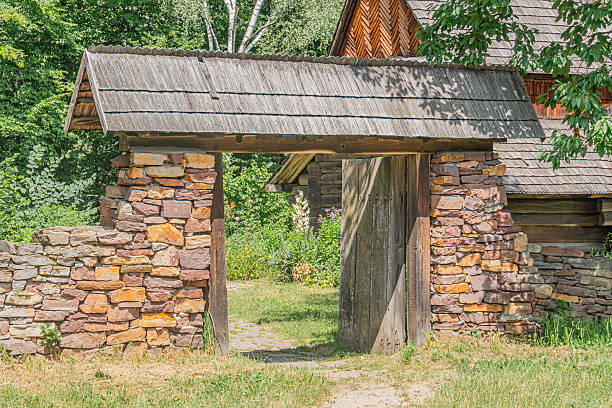 Ancient Central European stone cottage with a rustic archway, surrounded by lush greenery and gardens