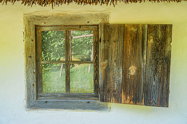istock Old rustic window in white-walled Central European building with thatched roof, exhibiting signs of age and animal hide covering Interior view reveals another window Vegetation and clear sky are vi 2230265336