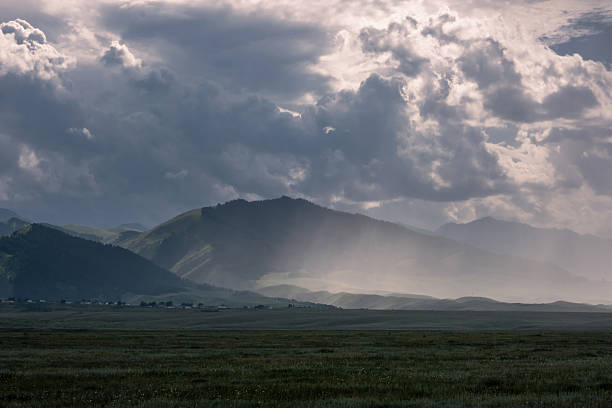 istock landscape featuring cloud-covered mountains and a wide field in the foreground. 2230266416