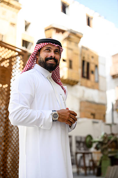 istock Smiling Middle Eastern man in a traditional attire looking up while standing confidently in a heritage district 2230268897