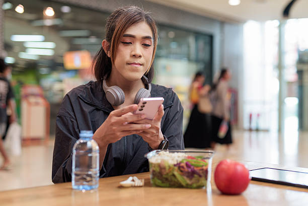 istock Transgender non binary woman texting with mobile phone while having healthy lunch after workout 2230270985