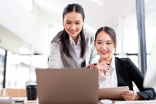istock A collaborative and friendly moment between two female business professionals as they work together on a laptop in a modern office. 2230274073