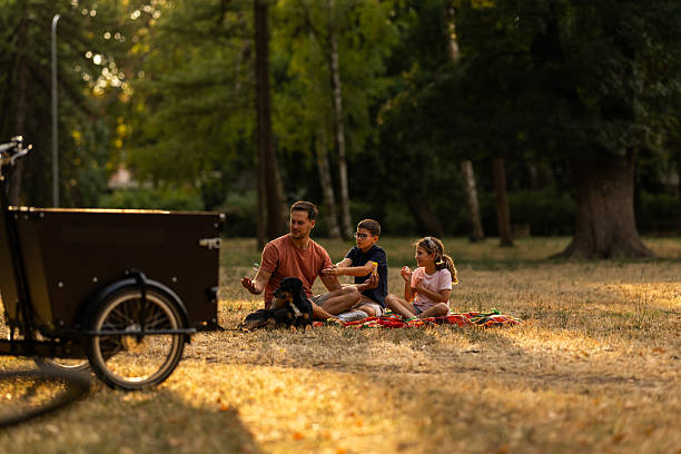 A family bonding over a picnic in a tranquil park, surrounded by trees and nature.