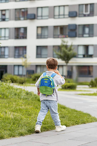 istock Little boy with backpack walking near apartments 2230279844