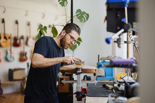 istock Luthier smoothing guitar body in workshop 2230283034