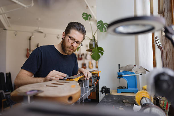 istock Luthier concentrating on restoring vintage guitar in workshop 2230283041
