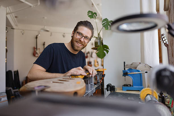 istock Luthier smiling while working on electric guitar neck in his workshop 2230283051