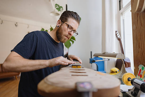 istock Luthier smoothing guitar neck in his workshop 2230283081