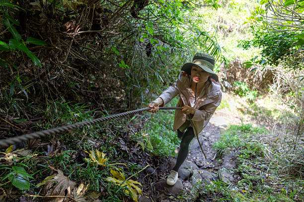 Female tourist climb up using rope in nature
