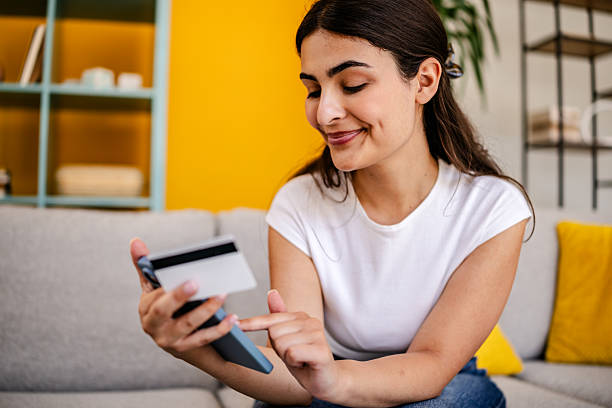 istock Young woman smiling while using her phone in a cheerful living room setting during the day 2230285430