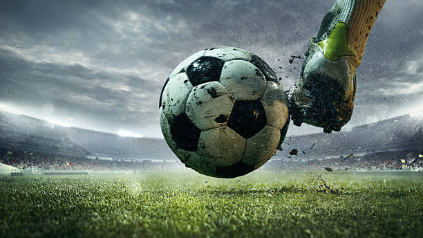 Soccer player kicking ball on rainy 3D stadium field during cloudy match