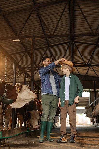 istock Dad trying out his hat on his son while they stand inside a barn 2230292541