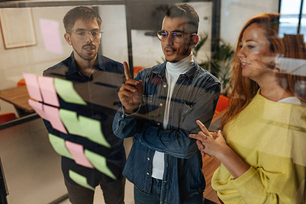 istock Business team brainstorming and planning using sticky notes on glass wall in office 2230292552