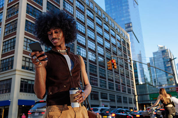 An urban scene with a stylish man using his smartphone, standing on a busy city street with buildings behind