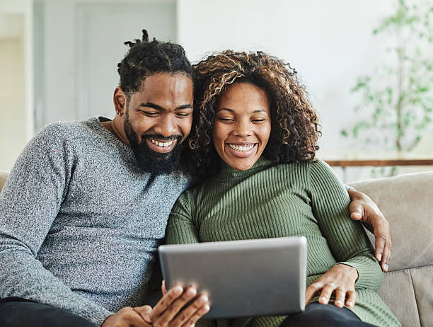 istock woman couple man happy internet love young tablet together computer technology online using sitting romantic happiness home reading device digital black 2230293579