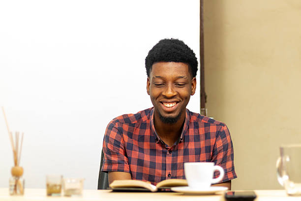 istock Smiling teen looking down while sitting at study table with coffee cup scented candles and diffusers 2230294079