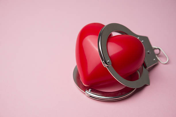 istock Red heart and handcuffs on pink background. 2230295244