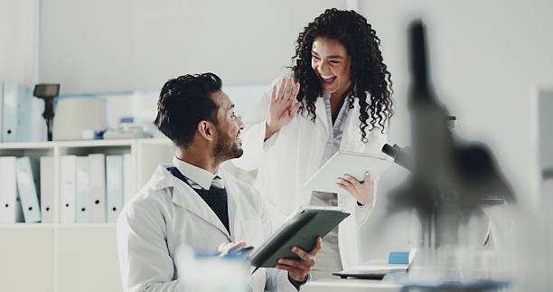 istock Happy, scientist and high five with tablet for research, medical discovery or forensic science. Excited, man and woman with smile or technology for success, teamwork or winning together at laboratory 2230295406