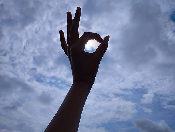 istock Hand Forming OK Gesture Framing the Sun in a Cloudy Sky 2230298656