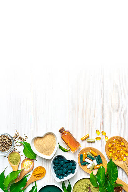istock Nutritional supplements and natural vitamins or healthy eating and dieting. Lower border on vertical white table with copy space. Healthcare or alternative medicine. Spirulina pills, Omega-3 capsules and essential oils 2230299314