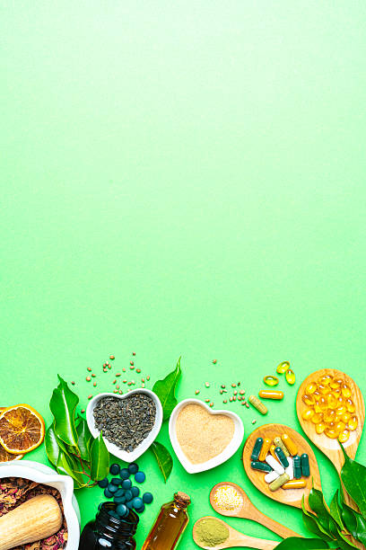 Nutritional supplements and natural vitamins or healthy eating and dieting. Lower border on green background with copy space. Healthcare or alternative medicine. Spirulina pills, Omega-3 capsules and essential oils