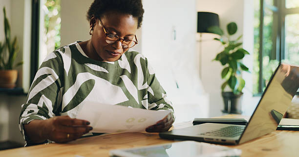 istock Reading, paperwork and woman with laptop, home and data analysis with tech, accountant or freelance. Review, financial report and black person with documents for bookkeeping, remote work and house 2230299991